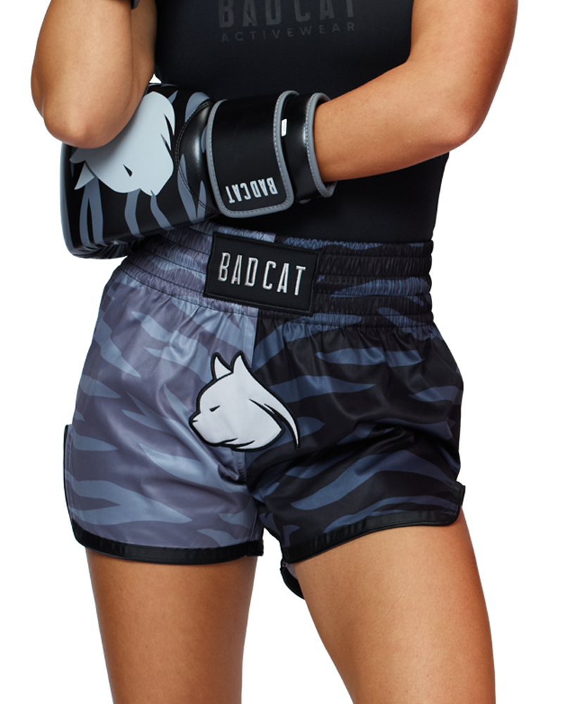 Woman wearing BAD CAT branded fight shorts and boxing gloves on a white background